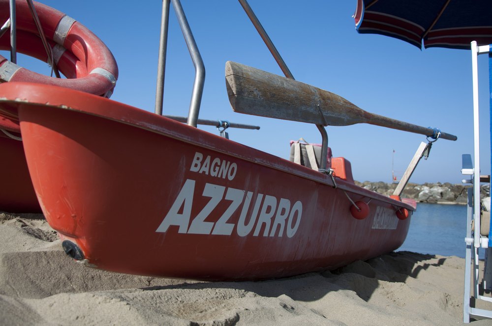 Il pattino di salvataggio del Bagno Azzurro sulla sabbia, con la scogliera di Marina di Pisa alle spalle