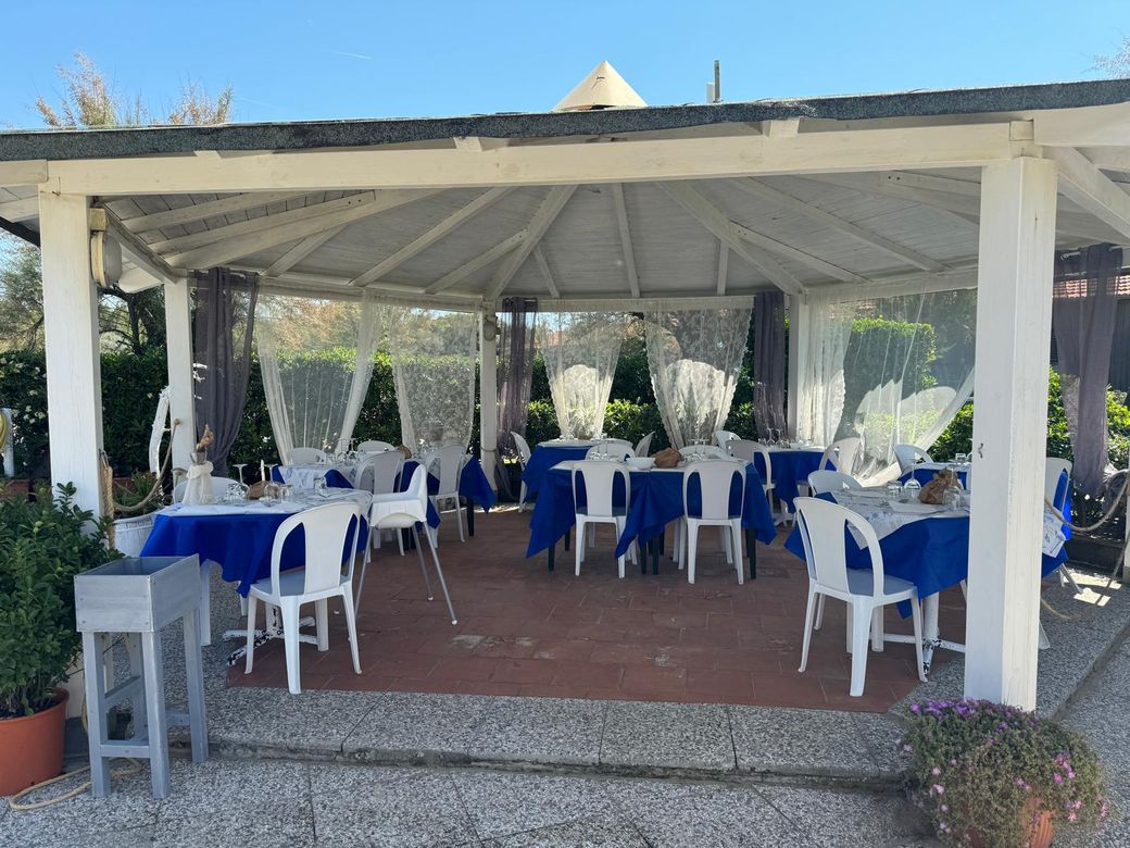L'area tavoli del ristorante Azzurro Sottocosta sotto il gazebo, con tovaglie blu e sedie bianche