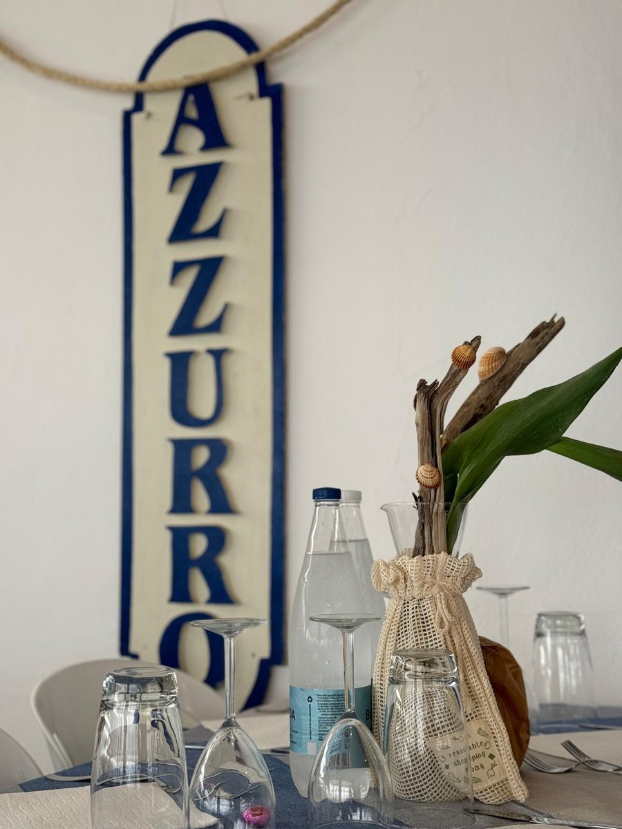 Tavola apparecchiata sotto l'insegna Azzurro del ristorante del Bagno Azzurro a Marina di Pisa